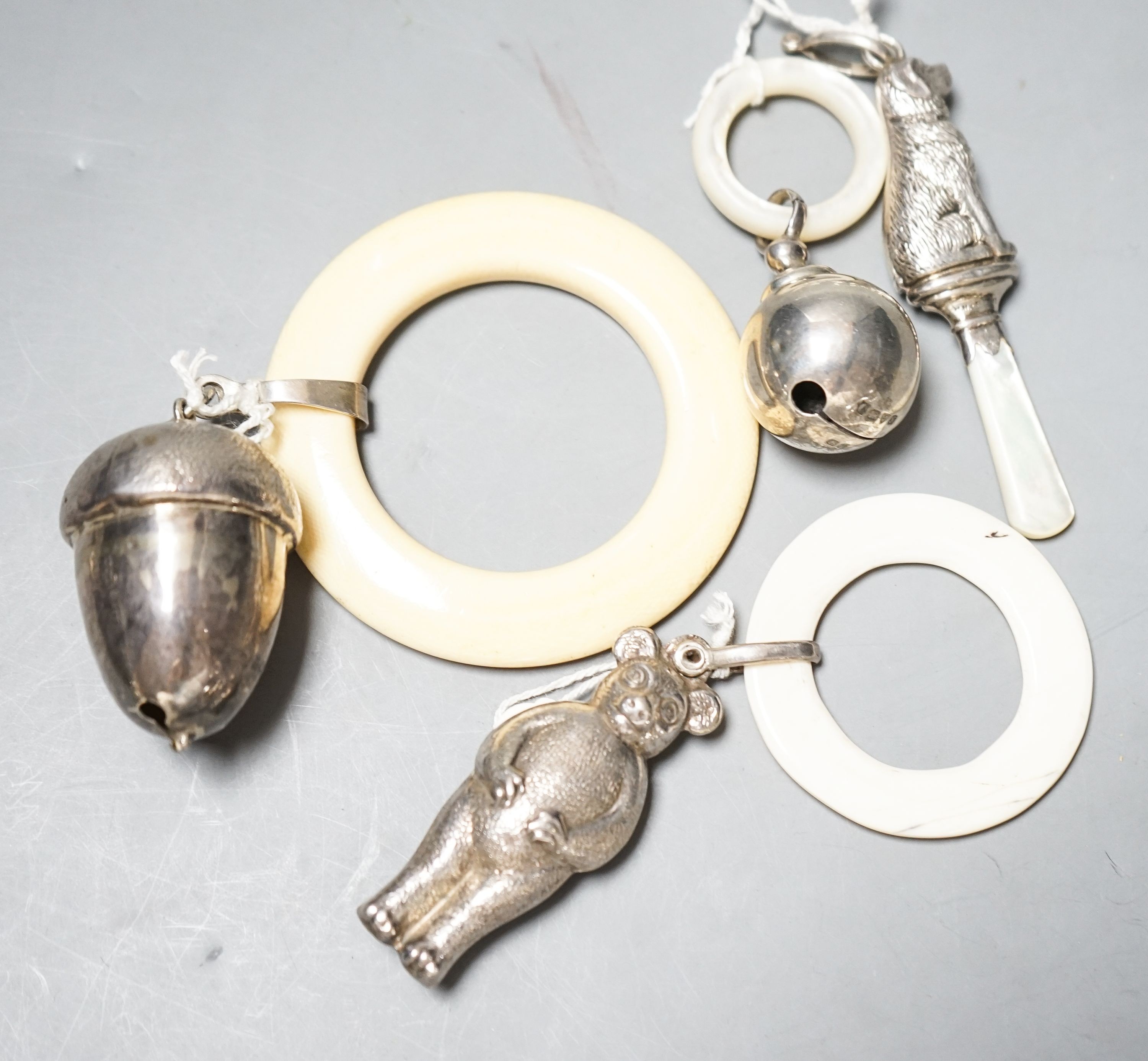 Four assorted child's silver and white metal teething rattles, including dog, bear and acorn.